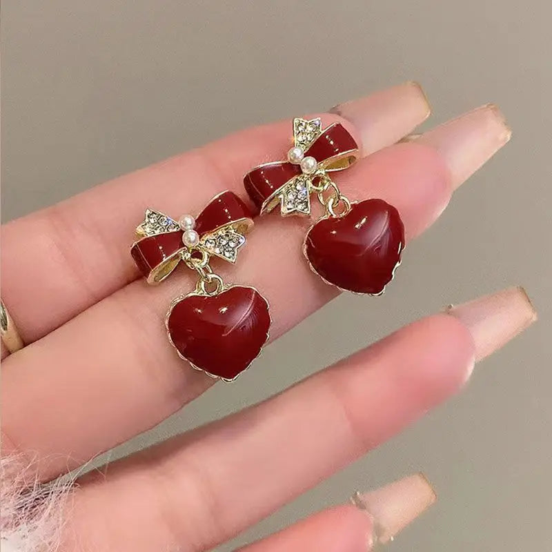 Pendientes de temperamento de nuevo estilo a la moda, pendientes de perlas de circón con forma de corazón de melocotón y lazo rojo vino, pendientes versátiles y exquisitos 2024